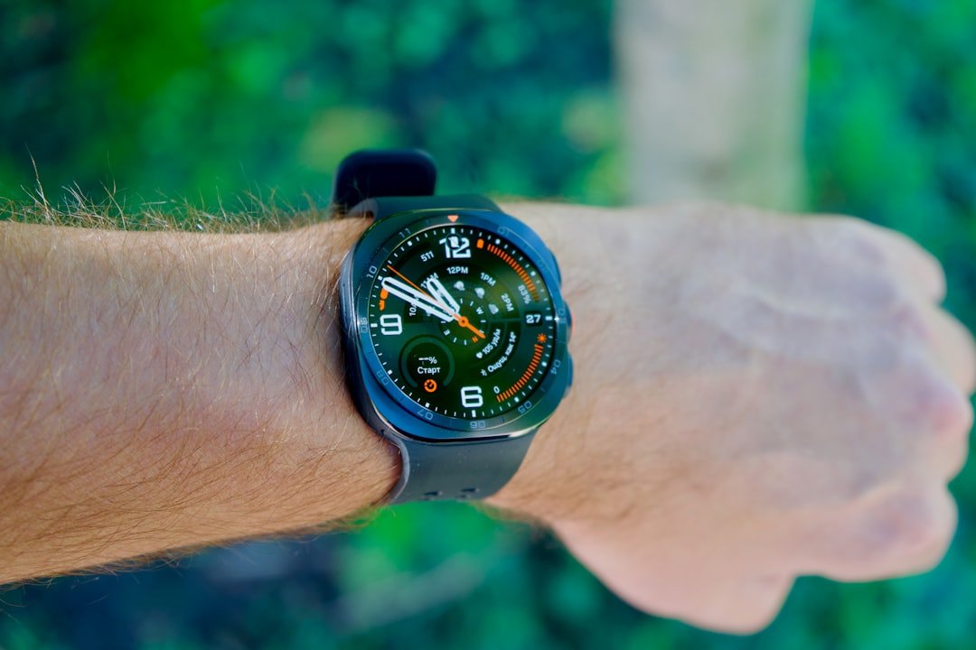A black smartwatch with a digital face on a person's wrist outdoors
