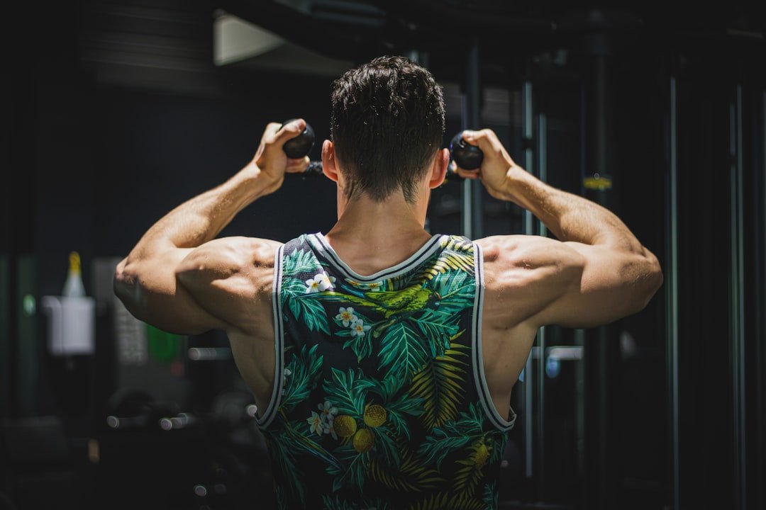 A man in a tank top is doing exercises in a gym