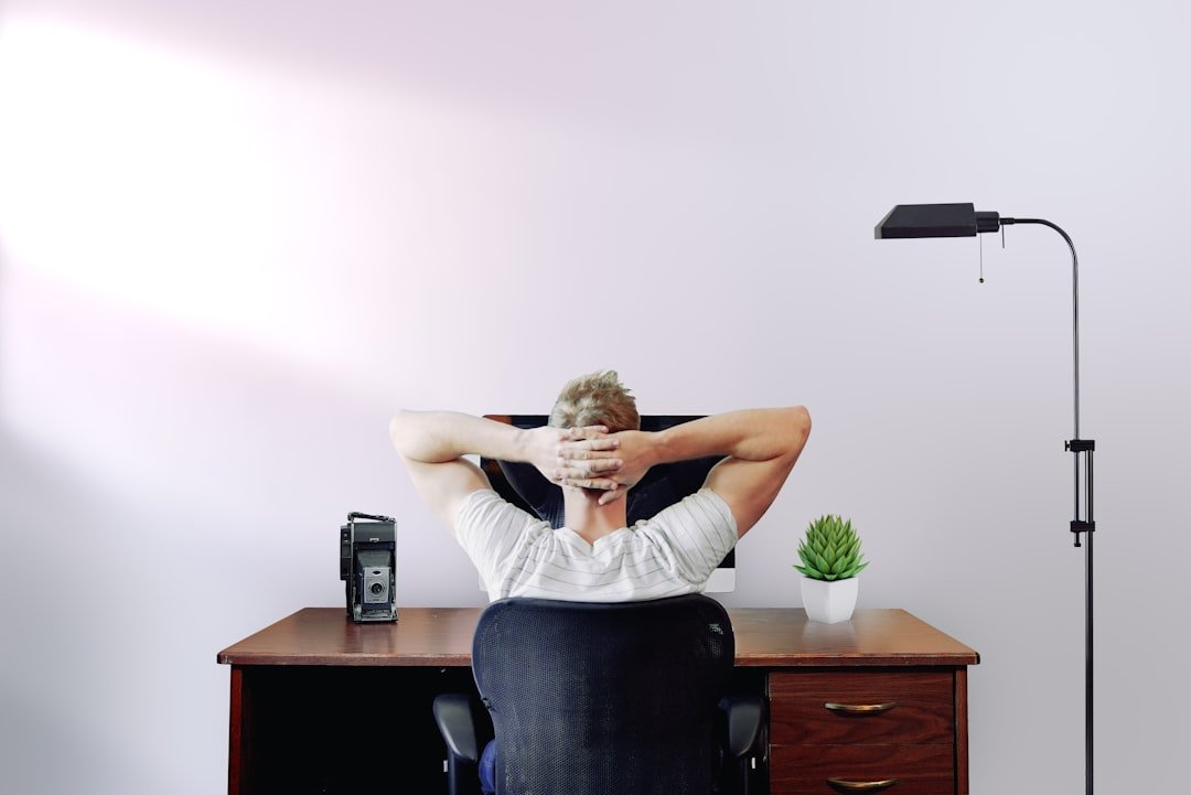 Desk stretches: Man holding his head while sitting on chair near computer desk