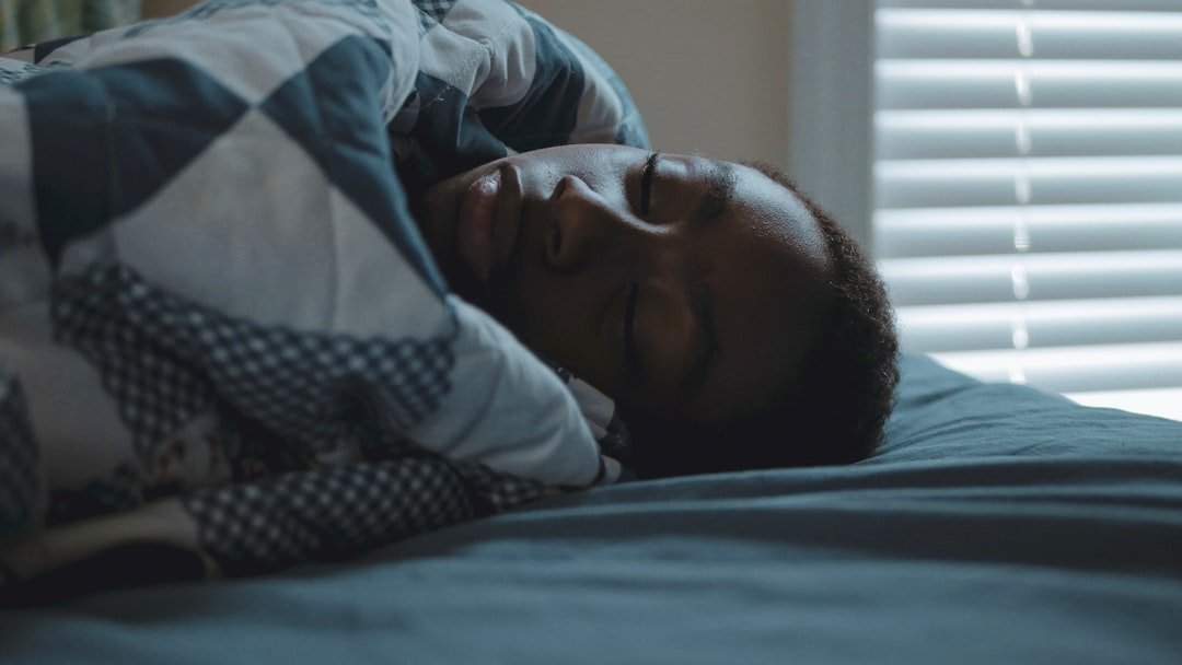 A person sleeping peacefully in bed under a patterned blanket