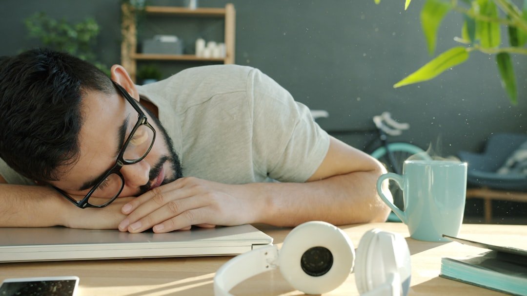 Man sleeping at desk with headphones and coffee