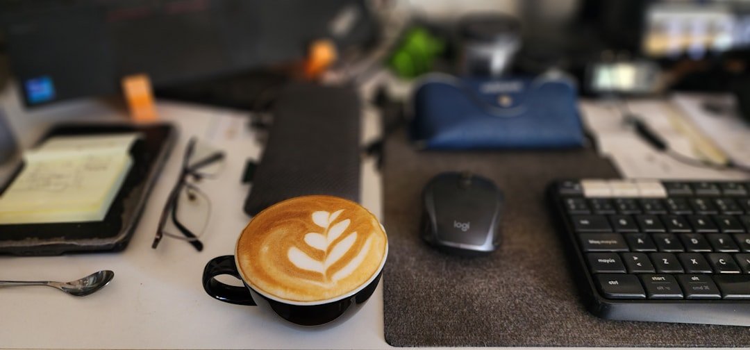 A cup of coffee sitting on top of a desk next to a keyboard