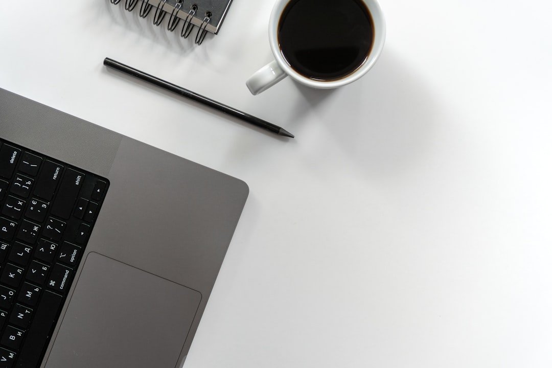 Laptop, coffee, pen, and notebook on a white desk