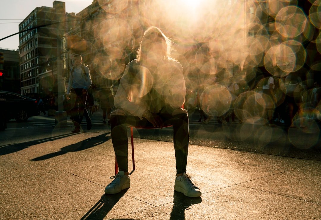 Person squats on street during sunrise