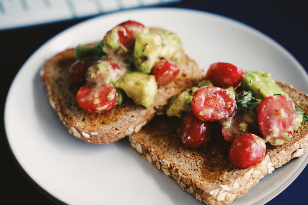 Bread with tomato and green vegetable on white ceramic plate