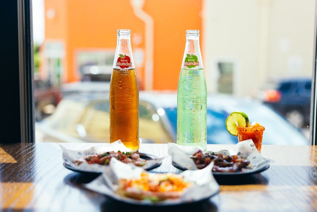 Two bottles of soda and a plate of food on a table