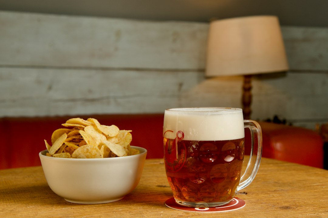A bowl of chips and a beer on a table