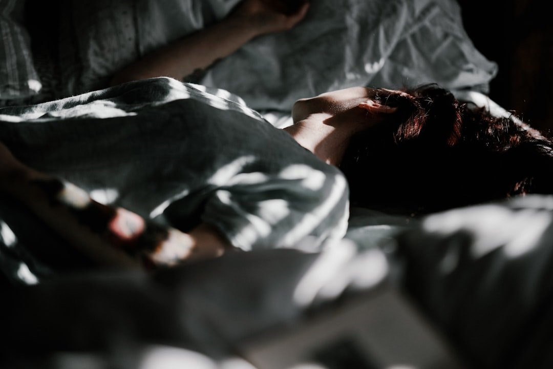 A person laying in a bed under a blanket
