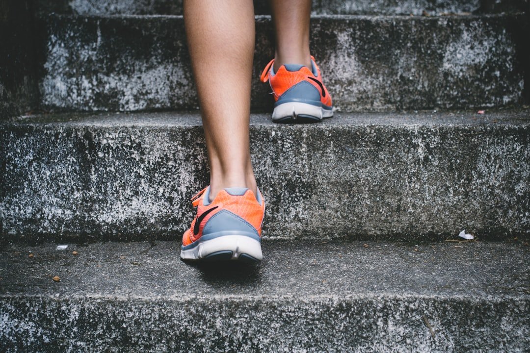 Person wearing orange and gray nike shoes walking on gray concrete stairs