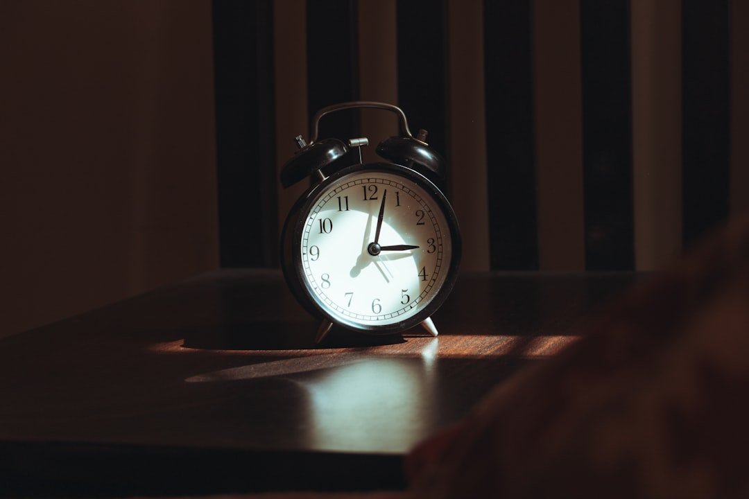 An alarm clock on a wooden table at night