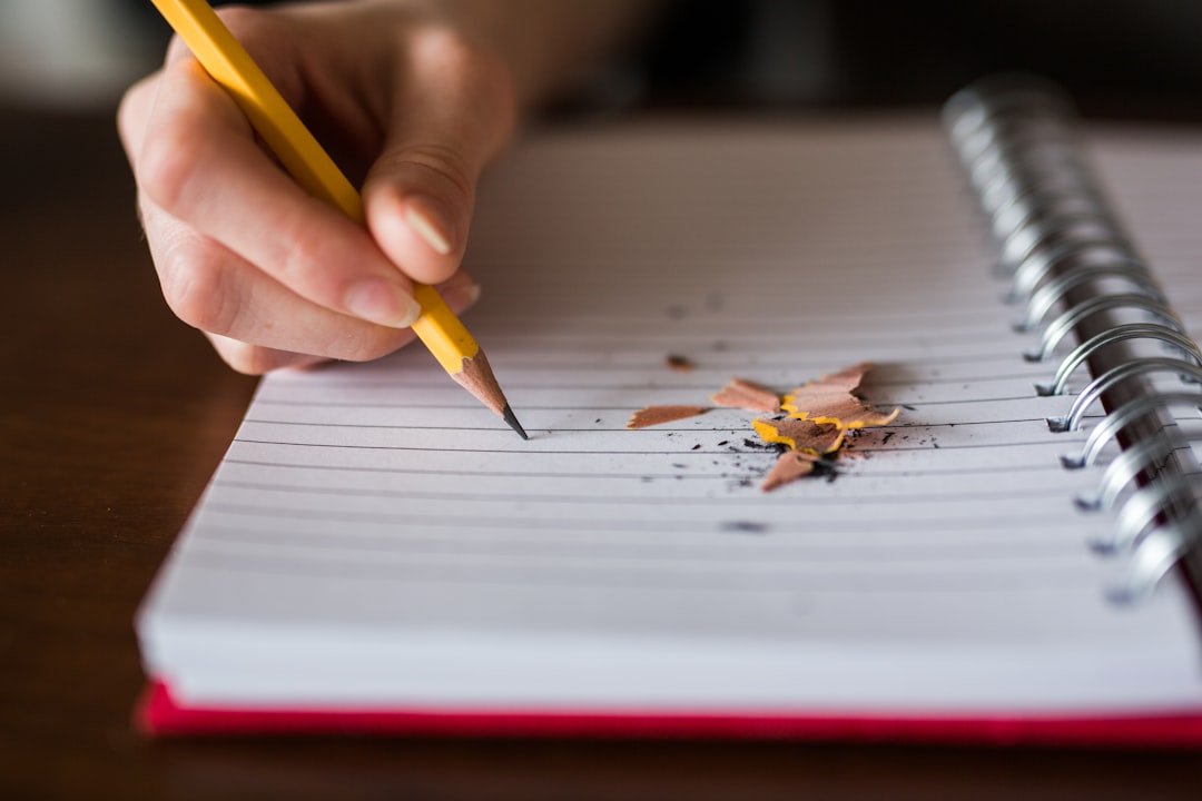 Person holding pencil writing on notebook