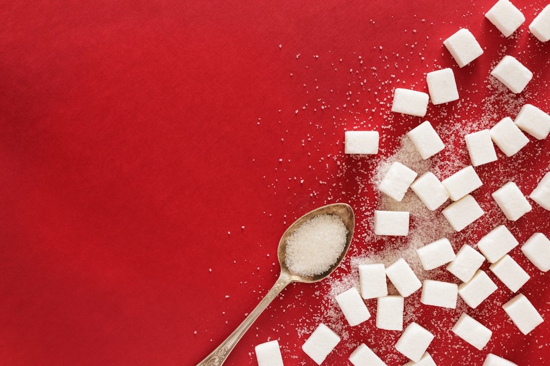 Sugar cubes and a spoon on a red surface