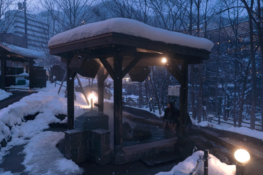 Snow falls on a covered outdoor hot spring