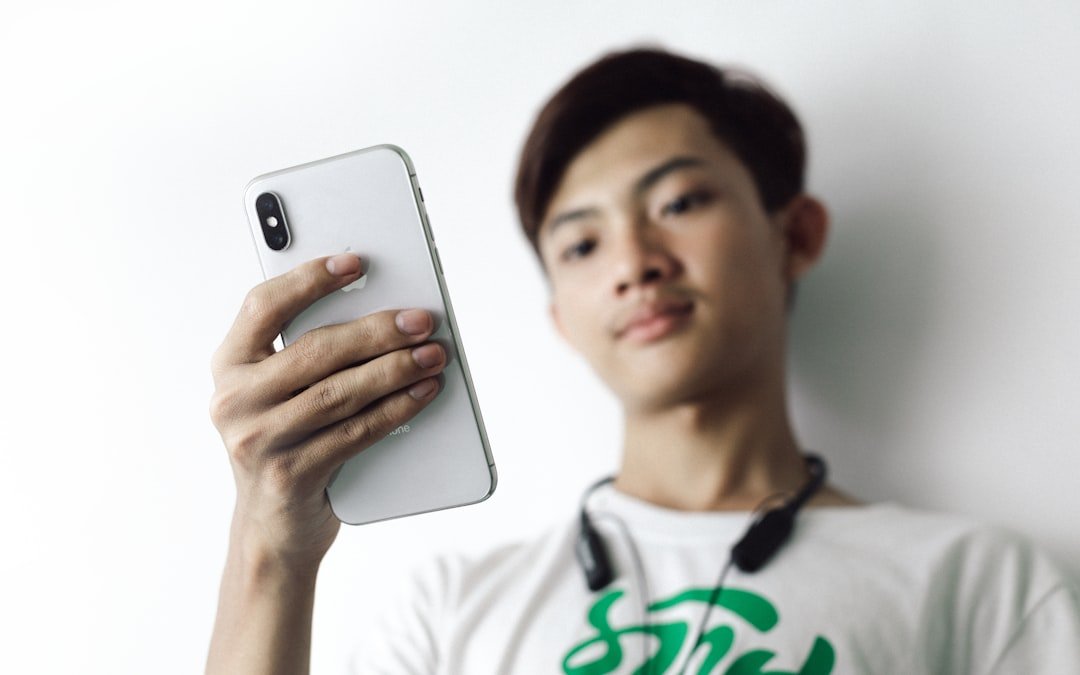 Man in white crew neck shirt holding silver iphone 6