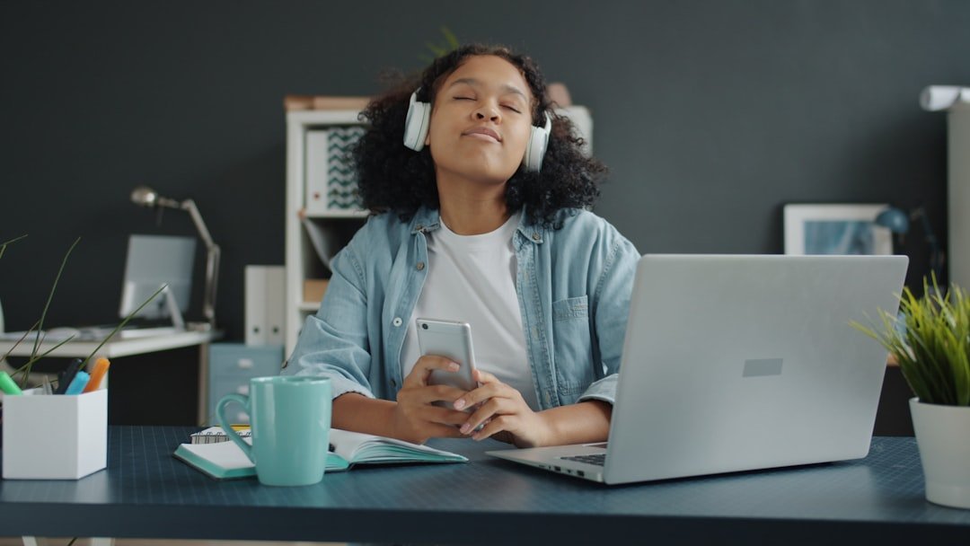 Young woman listening to music with headphones at desk