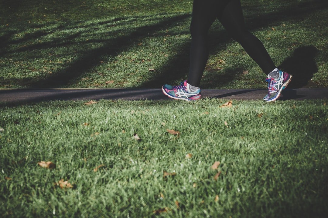 Shallow focus photography of person walking on road between grass