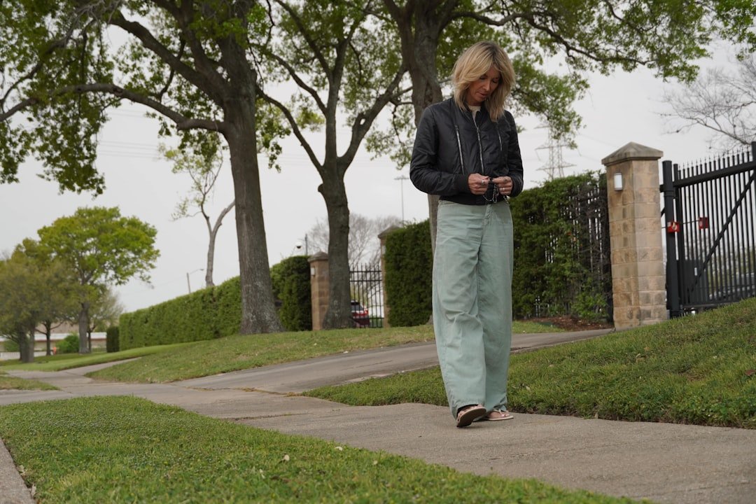 Woman walking on a sidewalk near a fence