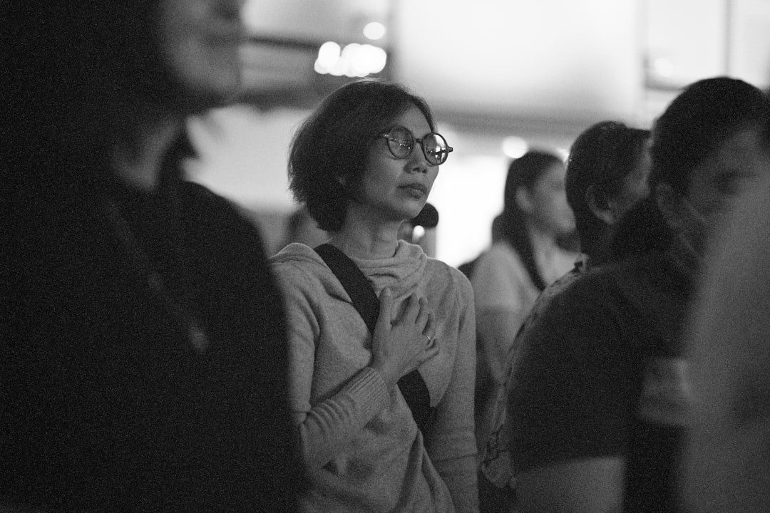 Woman in glasses with hand on chest looking away