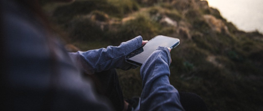 Person using a smartphone outdoors with blurred background