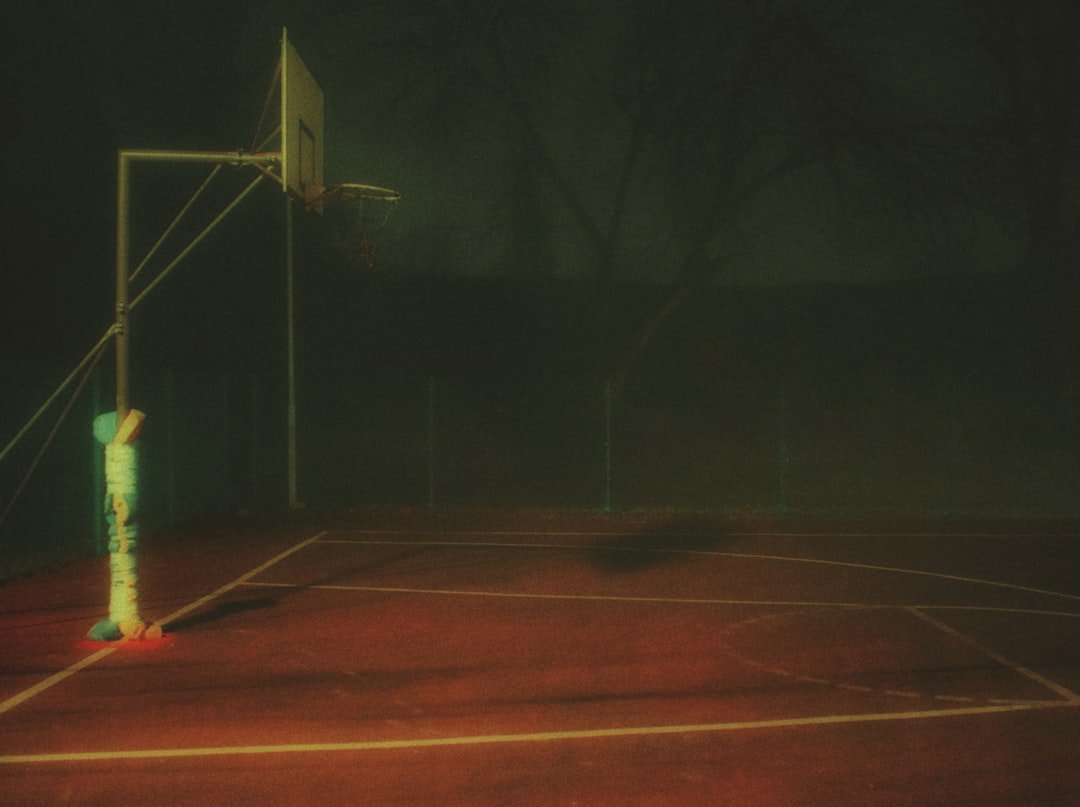 Foggy outdoor basketball court with a single hoop at night