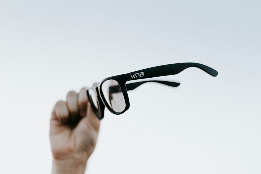 A hand holding up a pair of glasses